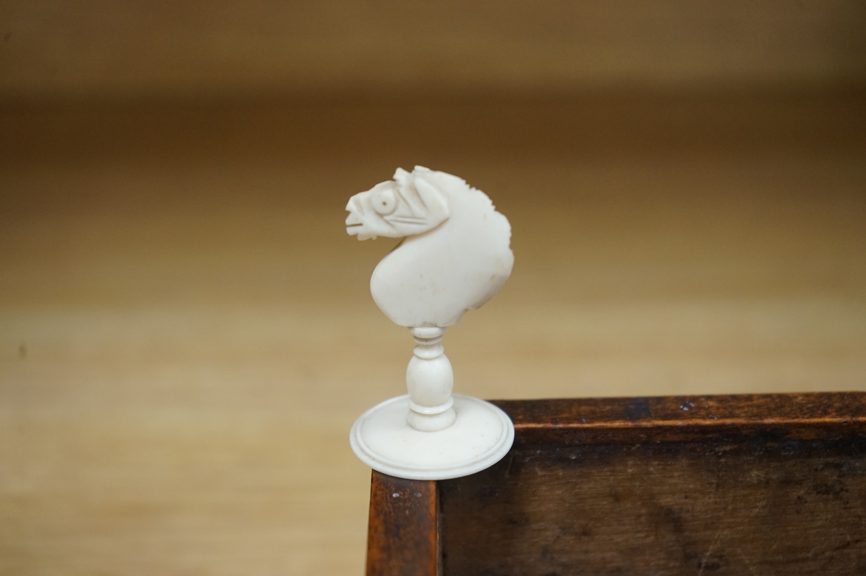 A 19th century games box with sliding cover carved with an eagle. The box containing a part bone stained chess set, box 28cm deep